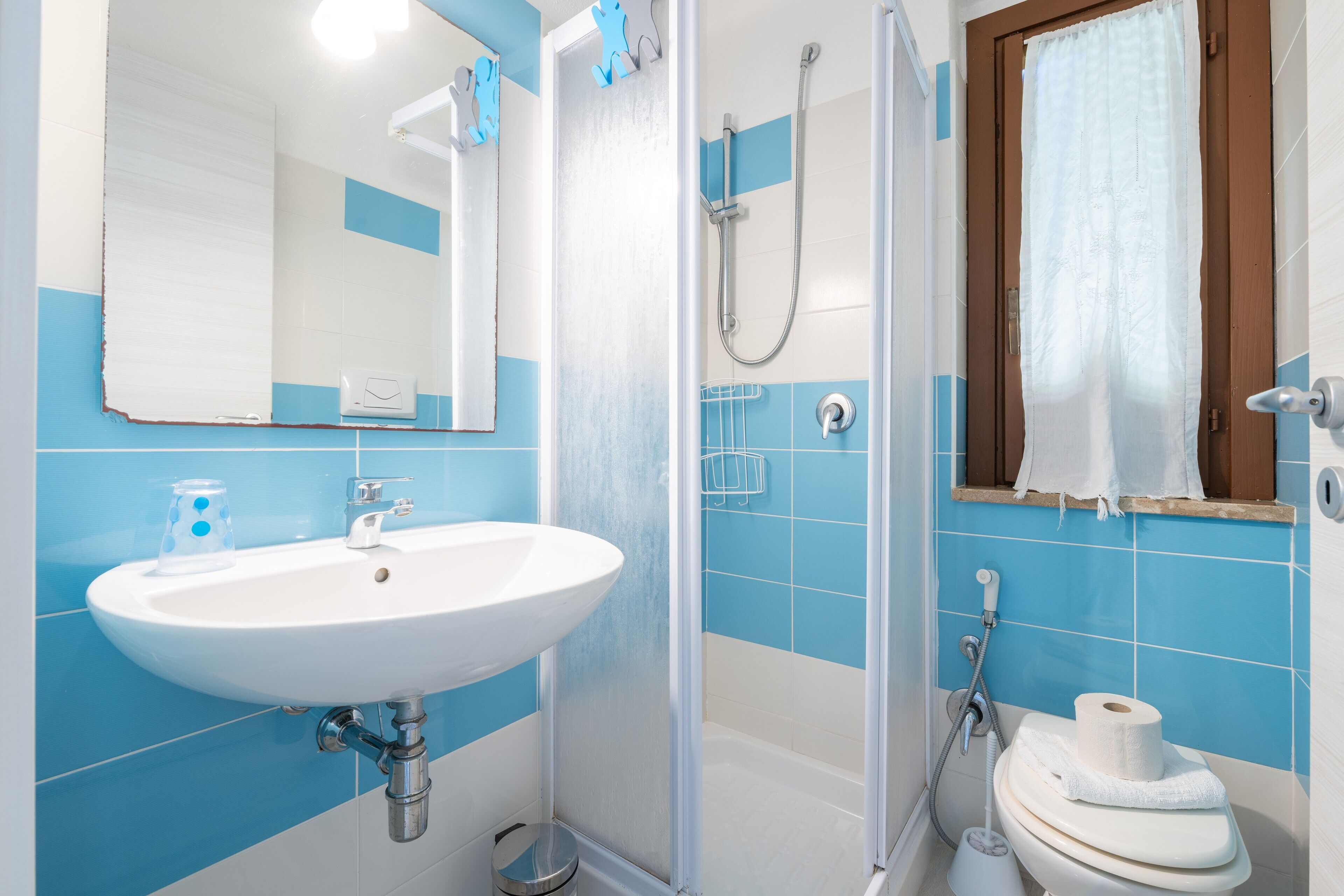 Ein Badezimmer mit Waschbecken, Spiegel, Dusche und Toilette.