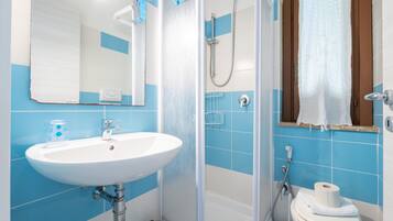 Ein Badezimmer mit Waschbecken, Spiegel, Dusche und Toilette.