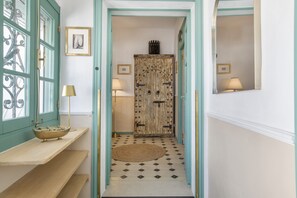Un pasillo con una puerta de madera, un tapete pequeño y un estante con un cuenco.