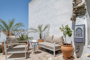 A terrace with a sofa, table, and potted plants. - Holiday Home 'Casa Castillo' - entire house, terrace, garden, with view over Vejer, Terrace & Wi-Fi (Vejer de la Frontera)