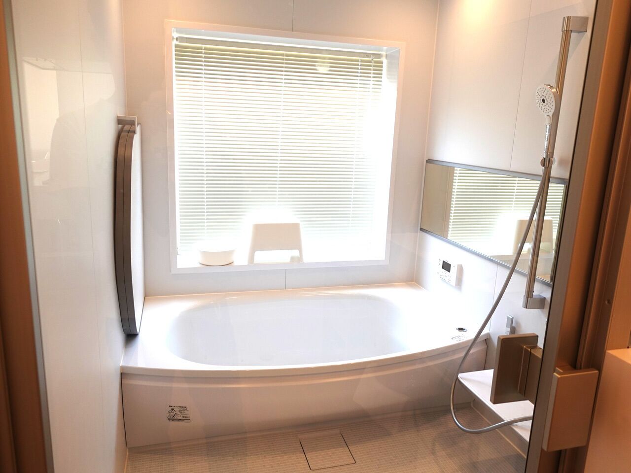 Une salle de bain moderne avec une baignoire sur pieds, une fenêtre avec stores, un espace douche et des toilettes.