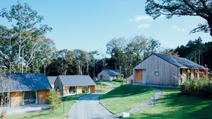 Un conjunto de cabañas modernas con un camino de grava que conduce a un área con césped, rodeado de árboles.