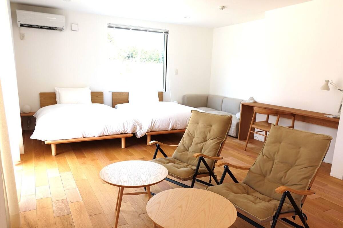 Un dormitorio moderno con dos camas, un sofá y dos mecedoras.