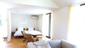 Una habitación de hotel moderna con sofá, cama, mesa de comedor y un amplio ventanal.