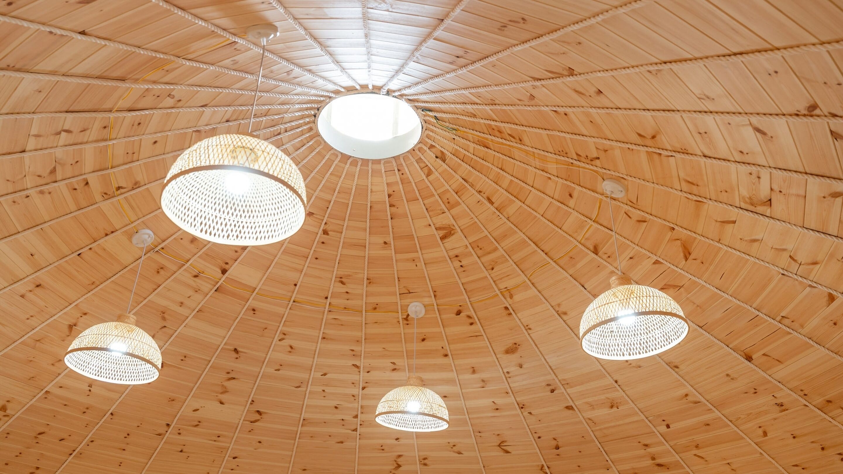 A wooden ceiling with a radial pattern and multiple hanging light fixtures.