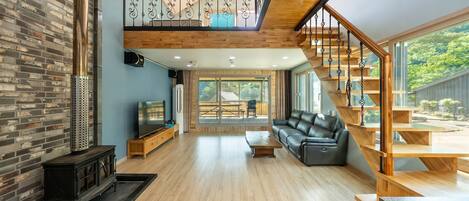 A spacious living area with a wooden staircase, a television, and a sofa.