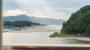 A coastal view with a beach, a gas station, and a forested area. - Samcheok Kong & Bee Ocean View Pension (Samcheok)