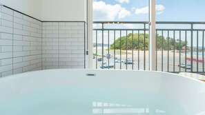 A bathroom with a bathtub and a view of a parking lot and beach. - Samcheok Kong & Bee Ocean View Pension (Samcheok)