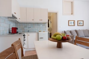 Une cuisine avec des meubles blancs, une machine à café rouge et une table à manger avec des chaises.