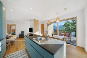 A modern kitchen with a large island, a dining area with a table and chairs, and a view of the outdoors. - Holiday Apartment 'Plattwies' with Mountain View, Private Terrace and Wi-Fi (Unknown)