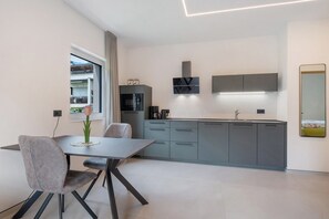 A modern kitchen with grey cabinets, a built-in oven, and a window with curtains.