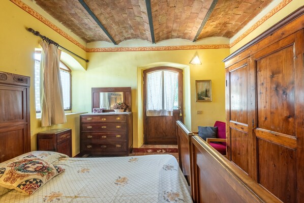 Una habitación con cama, armario de madera, cómoda y espejo.