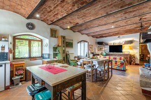 Una cocina rústica con una mesa de madera, sillas y piso de baldosas.