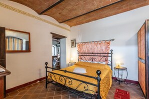 Un dormitorio con cama, dos lámparas de noche, una puerta de madera y piso de baldosas.