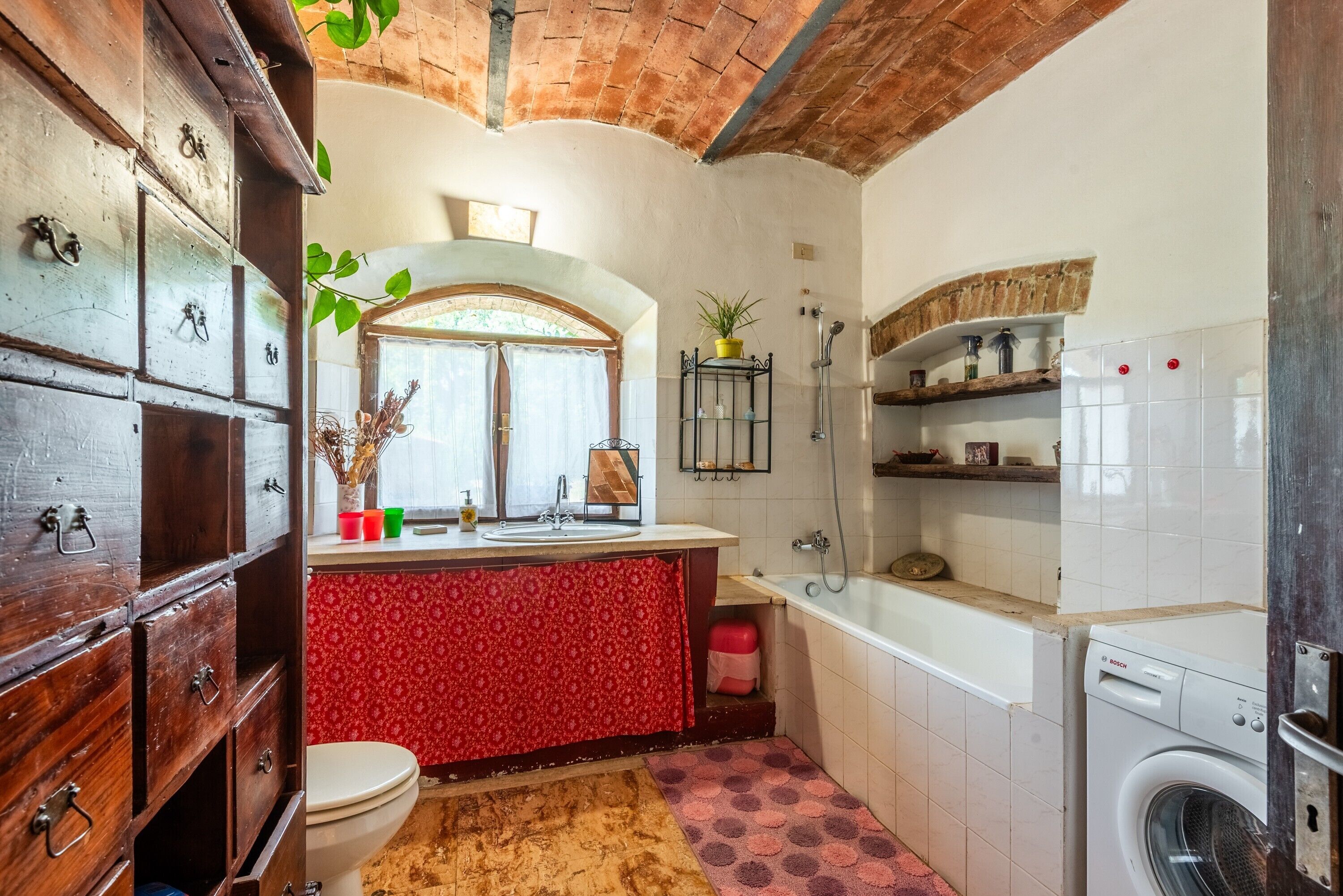A compact bathroom with a toilet, sink, shower, and washing machine.