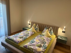 A bed with patterned bedding, two bedside tables, and wall-mounted lights. - Apartment 'Rosalie  3' with Mountain View, Shared Pool and Wi-Fi (Lana)
