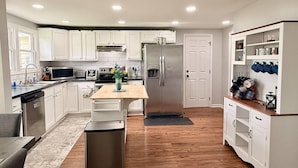 Una cocina moderna con armarios blancos, electrodomésticos de acero inoxidable y una isla de madera.