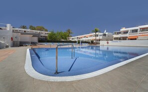 A swimming pool with a tiled deck, lounge chairs, and a lifebuoy. - Holiday Studio 'A T Suite' with Shared Pool and Wi-Fi (Costa del Silencio)