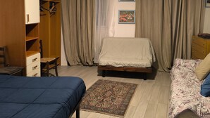 A bedroom with a bed, a wardrobe, a desk, and a chair.