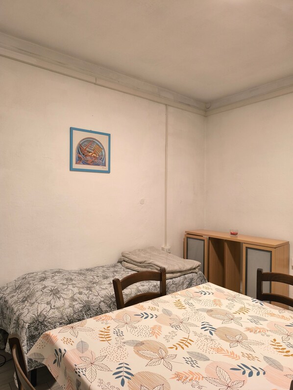 Una habitación con cama, escritorio y silla. Hay un cuadro en la pared.