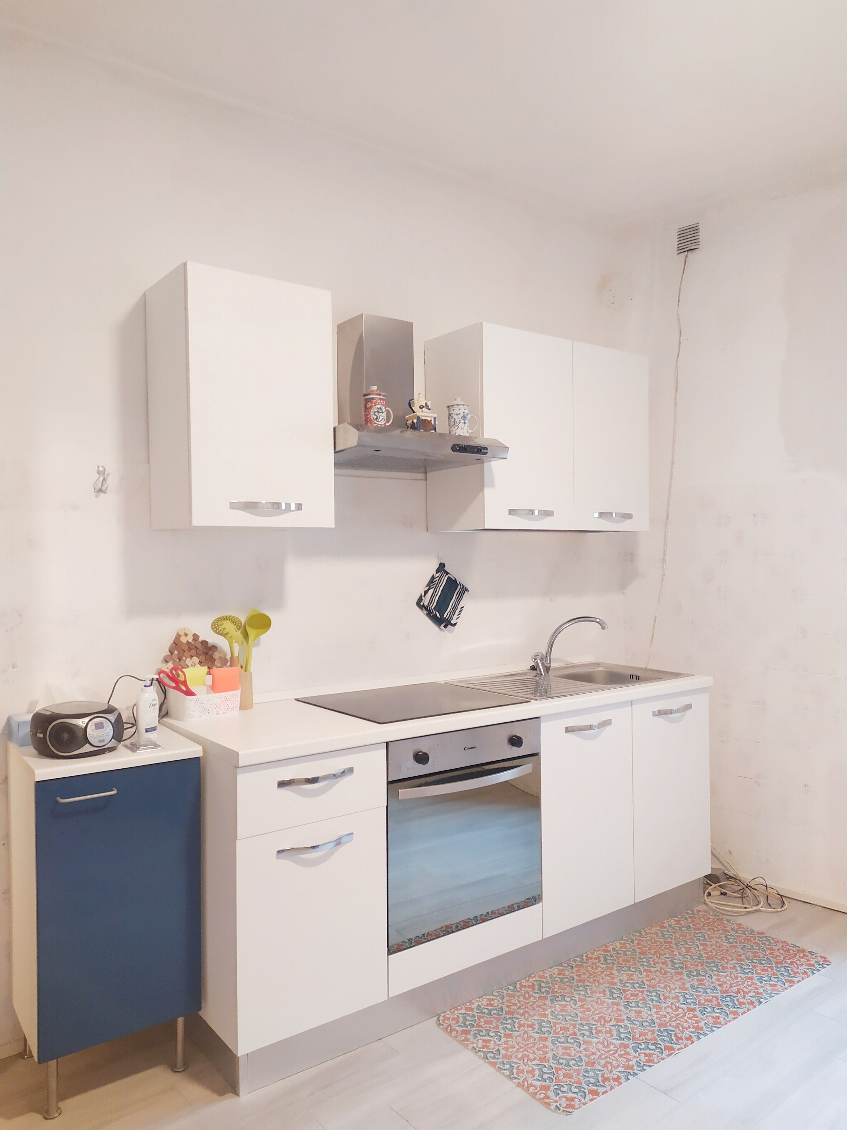 Een koelkast, een oven, een kookplaat, kookgerei, borden en bestek