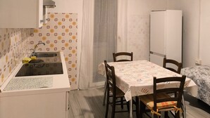 A compact kitchen with a sink, a dining table with chairs, and a refrigerator.