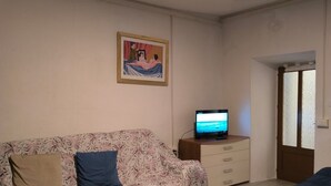 A room with a sofa, a television, a patterned rug, and a painting on the wall.