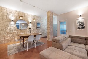 Un coin repas agrémenté d’un mur en pierre, d’un miroir rond, de luminaires suspendus et offrant une vue sur une autre pièce.