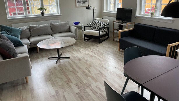 Un salon moderne comprenant un canapé, un fauteuil, une table basse et un téléviseur.