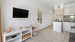 Een moderne woonkamer met een flatscreen televisie, een kleine plant en een houten plank.