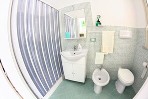 A bathroom with a sink, bidet, toilet, and a striped shower curtain.