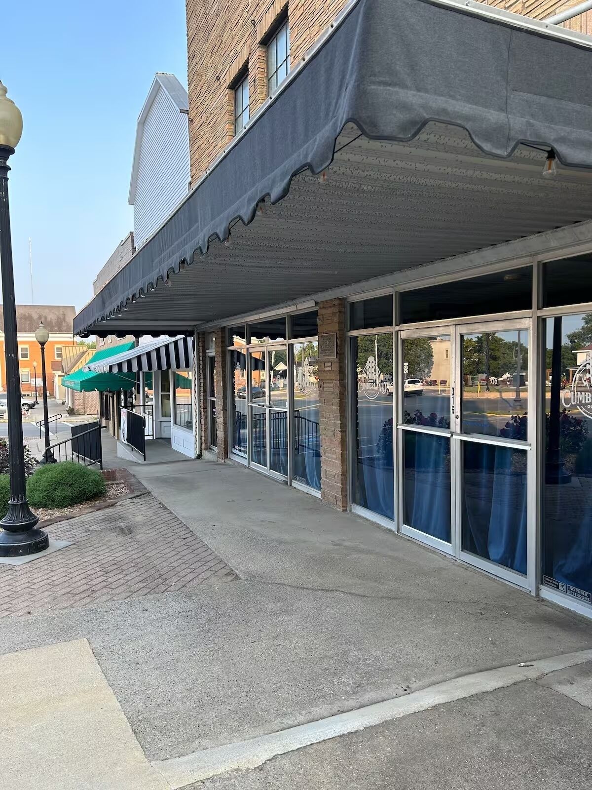 A building with a covered entrance, large windows, and a brick facade.