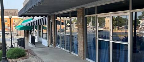 A building with a covered entrance, large windows, and a brick facade.