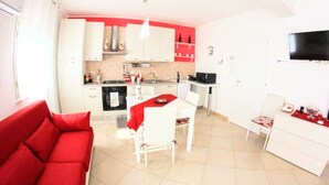 A compact living space with a kitchenette, a dining area, and a red sofa. - 'Corallo - Casa Vacanze' Apartment with Sea View, Wi-Fi and Air Conditioning (Balestrate)