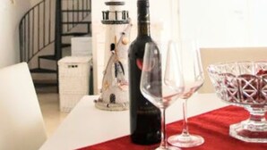 A dining table with a wine bottle and glasses, a decorative lighthouse, and a spiral staircase in the background. - 'Corallo - Casa Vacanze' Apartment with Sea View, Wi-Fi and Air Conditioning (Balestrate)