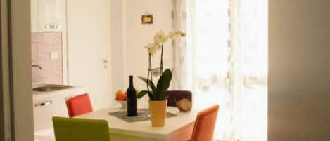 A dining area with a table, chairs, and a potted plant.