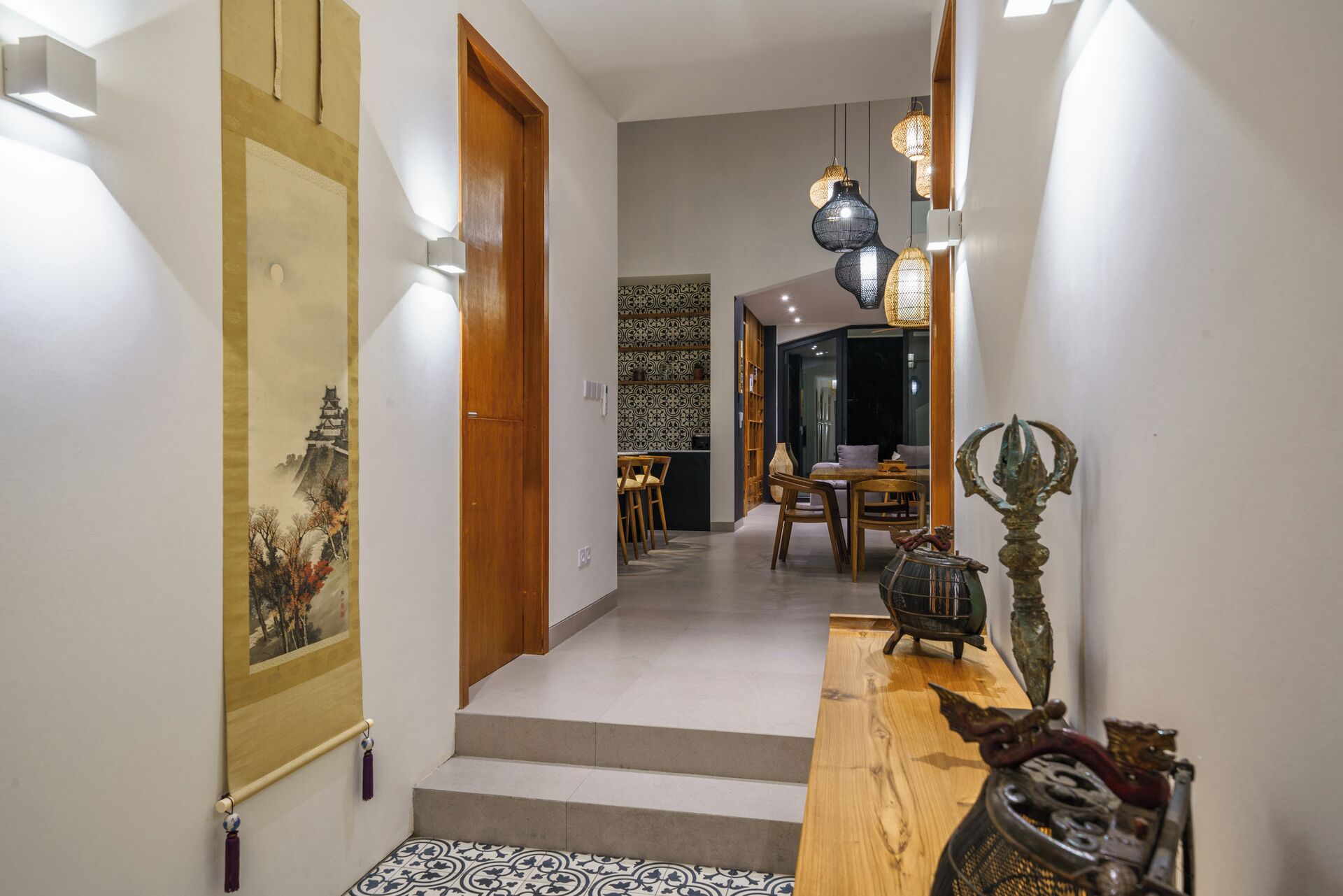 A hallway with a wooden door, a dining area with a table and chairs, and decorative items on a console table.