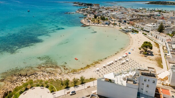 An aerial view of a coastal town with a beach, buildings, and a clear blue sea. - Holiday Home 'Lola' with Private Terrace, Private Garden and Air Conditioning (Porto Cesareo)