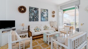 A modern living room with a sofa, coffee table, and chairs, a flat-screen TV, and artwork on the walls. - Holiday Home 'Lola' with Private Terrace, Private Garden and Air Conditioning (Porto Cesareo)