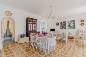 A dining area with a round table, white chairs, and a patterned floor.