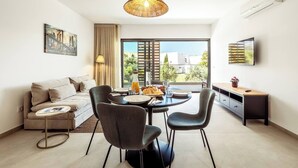 A modern living room with a dining area, a sofa, a coffee table, and a TV.