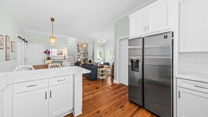 Une cuisine moderne avec des meubles blancs, des appareils en acier inoxydable et un plancher en bois.