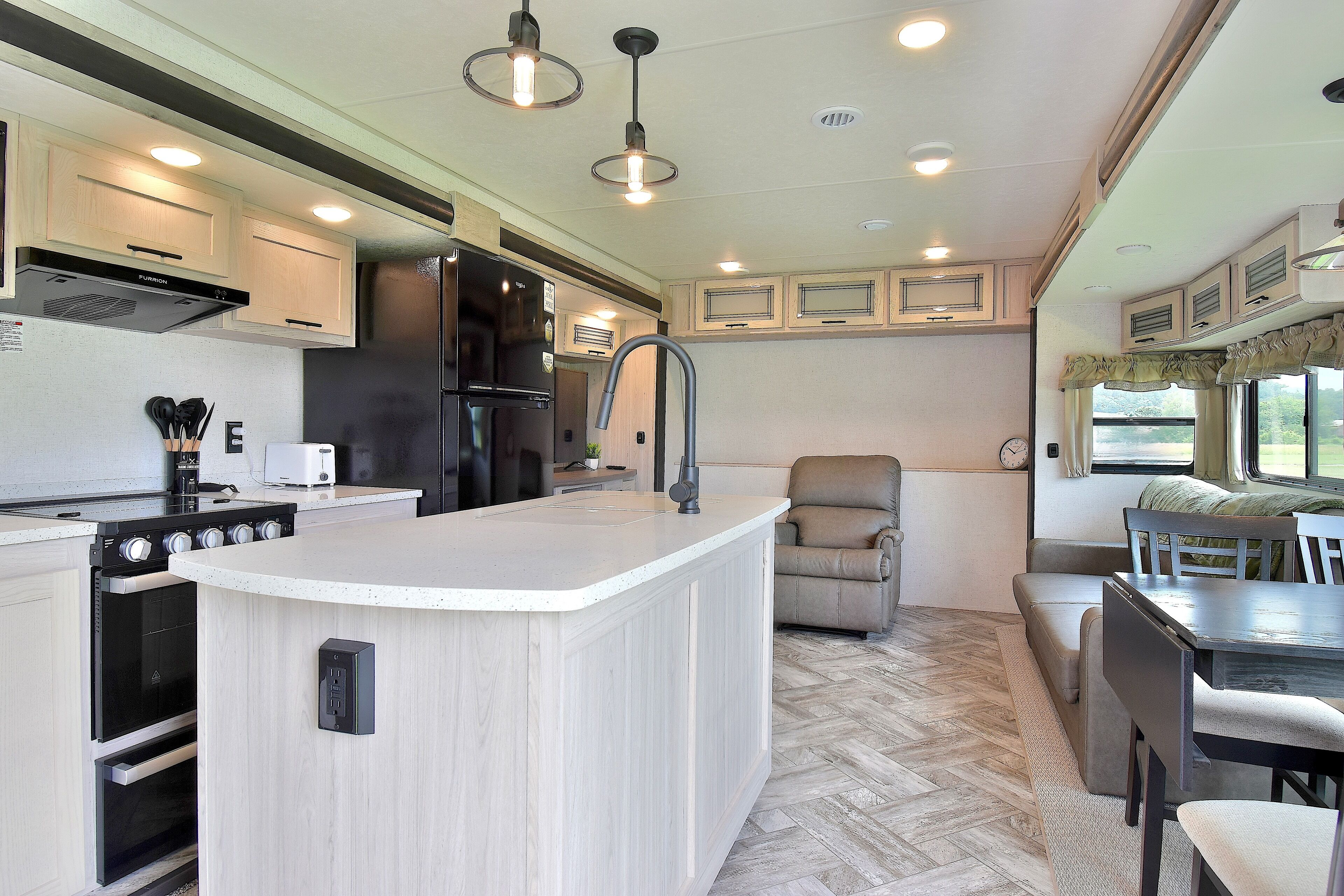 A compact kitchen with a central island, built-in appliances, and a dining area with a bench.