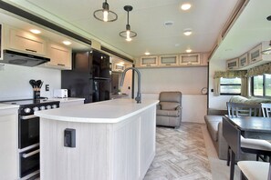 Una cocina compacta con una isla central, electrodomésticos integrados y una zona de comedor con banco.