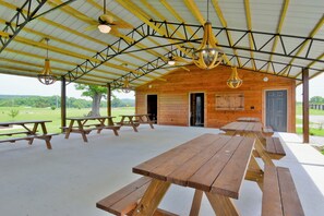 A covered picnic area with wooden benches and tables, a wooden building with a door and windows, and a view of the outdoors. - The Twin Pines Escape -9 (Decatur)