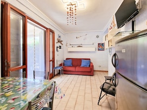 Una cocina compacta con una mesa de comedor, un sofá rojo y un refrigerador.