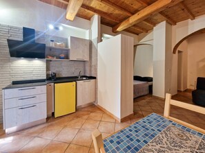 Une petite cuisine équipée d’un évier, d’une cuisinière et d’un réfrigérateur jaune.