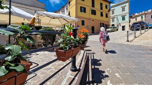 A street with a woman walking, buildings, and potted plants. - Apartment 'Gianni Rio Elba' with Wi-Fi and Air Conditioning (Rio Nell'elba)