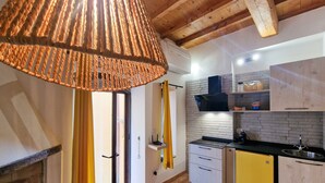 A kitchen with a hanging light fixture, a brick wall, and wooden beams. - Apartment 'Gianni Rio Elba' with Wi-Fi and Air Conditioning (Rio Nell'elba)