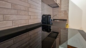 A kitchen with a brick backsplash, a black countertop, and a coffee machine. - Apartment 'Gianni Rio Elba' with Wi-Fi and Air Conditioning (Rio Nell'elba)